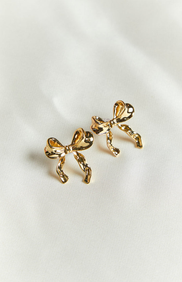 Pair of gold bow earrings with a textured, crinkled finish shown from an elevated angle