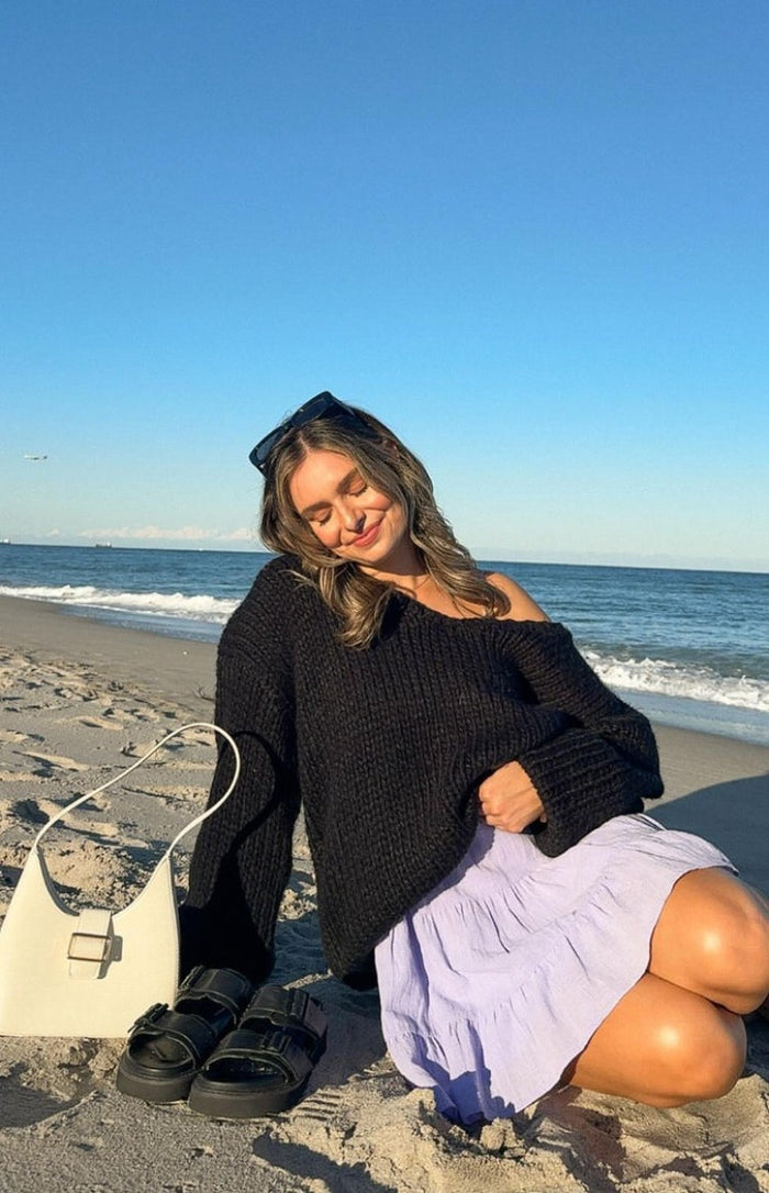 Black chunky knit sweater with a wide off-shoulder neckline and long sleeves