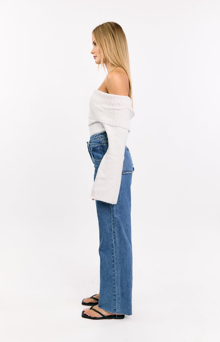 Side view of mid wash denim wide leg jeans with an uneven waistline and frayed hem