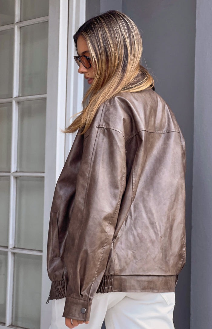 Side view of an oversized vintage brown PU bomber jacket with dropped shoulders and elasticated hem
