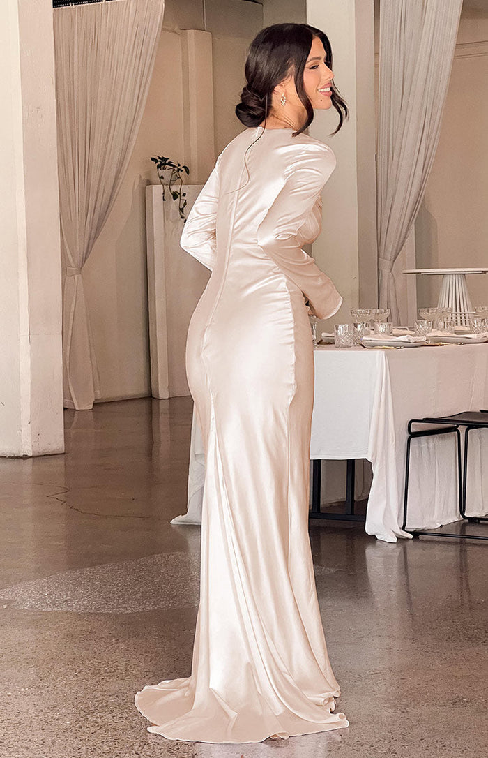 Rear and side view of a cream long sleeve maxi dress with a fitted silhouette, side ruching, and floor-length hem