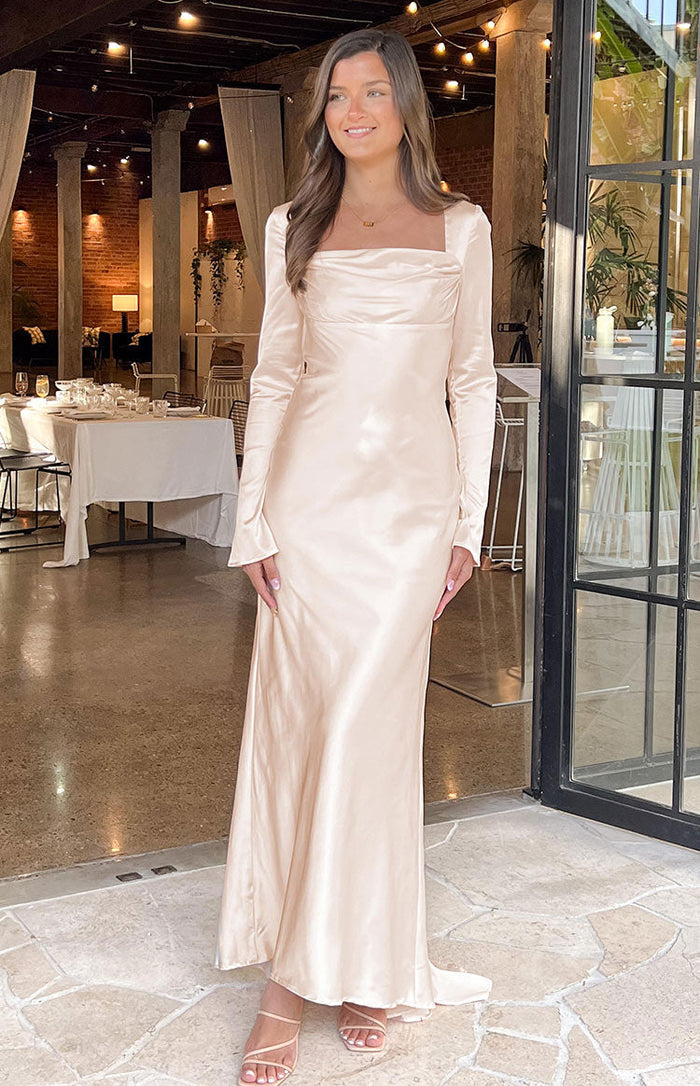 Cream long sleeve maxi dress with a square neckline, draped bust detail, and flowing satin skirt