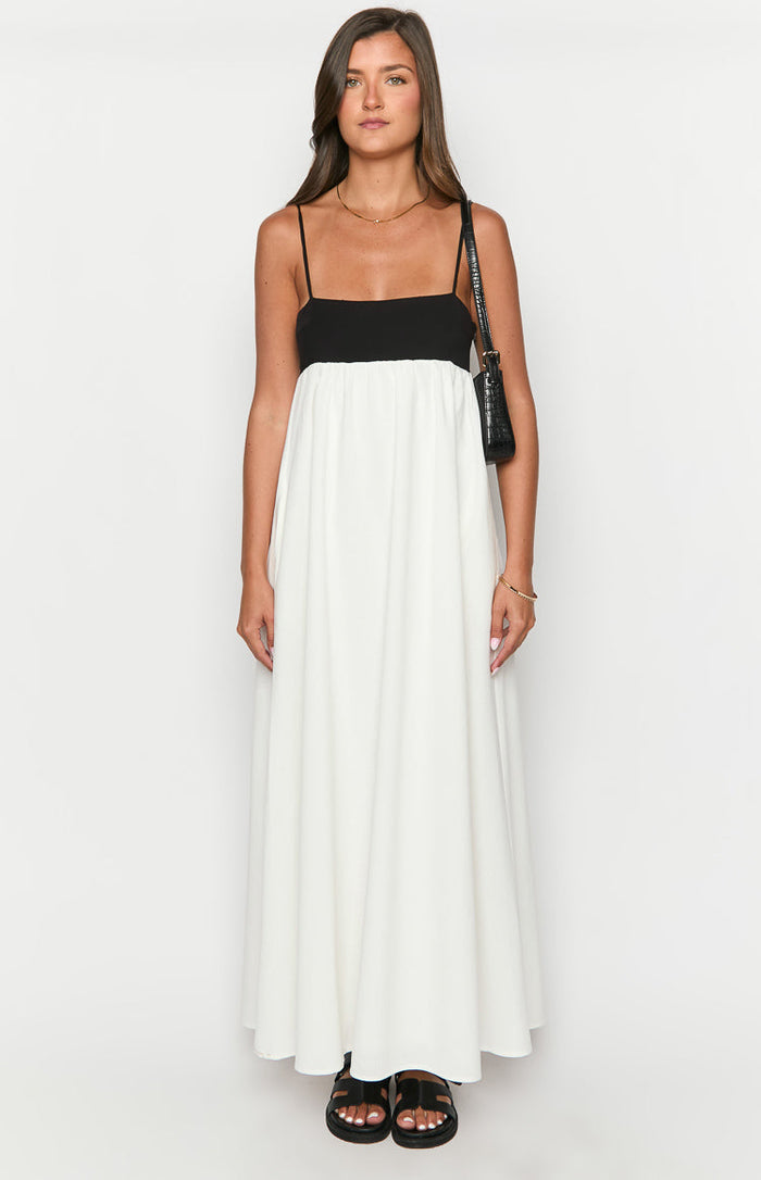 Front view of a black and white contrast maxi dress with a square neckline, thin spaghetti straps, and a flowy white skirt