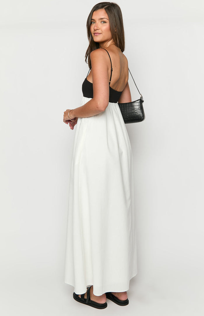 Side view of the black and white contrast maxi dress, showing the black fitted bodice with thin spaghetti straps and a low scoop back