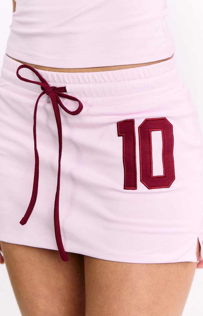 Close-up of the pink jersey skort showing the elasticated waist with burgundy drawstring and embroidered number 10