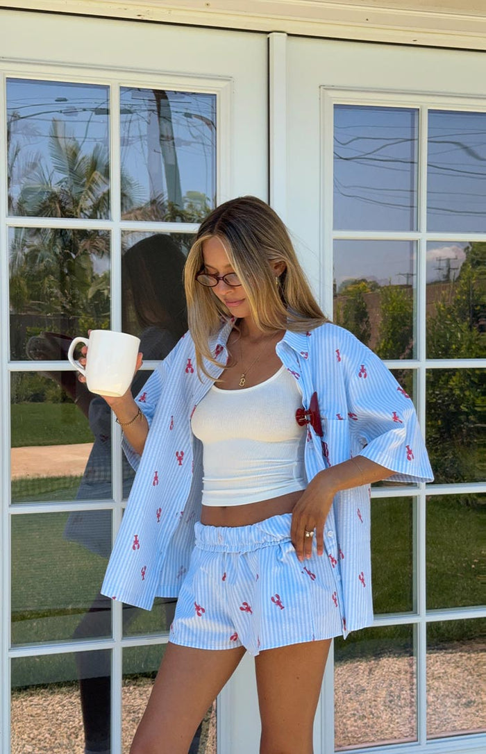 Light blue and white striped lobster print pajama shirt worn open, showing matching elasticated shorts