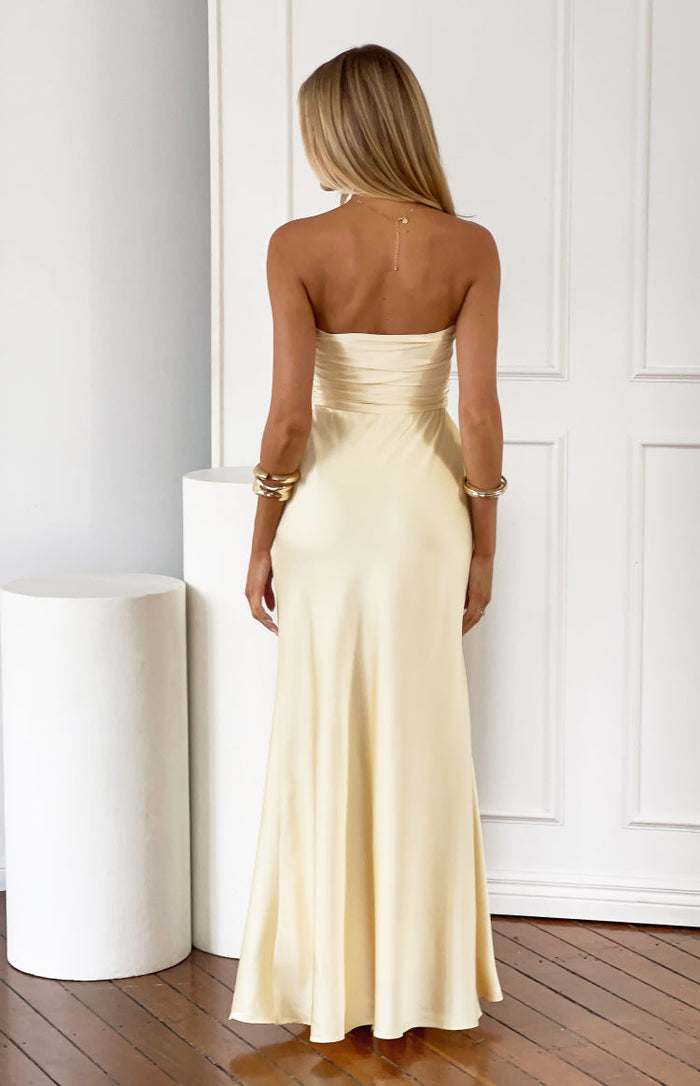 Rear view of a light yellow strapless maxi dress with a ruched detail across the back of the bodice