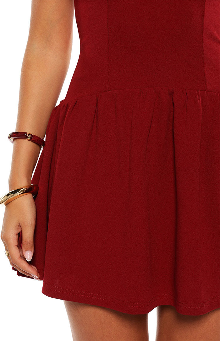 Close-up of the gathered waist and flowing skirt of a burgundy mini dress