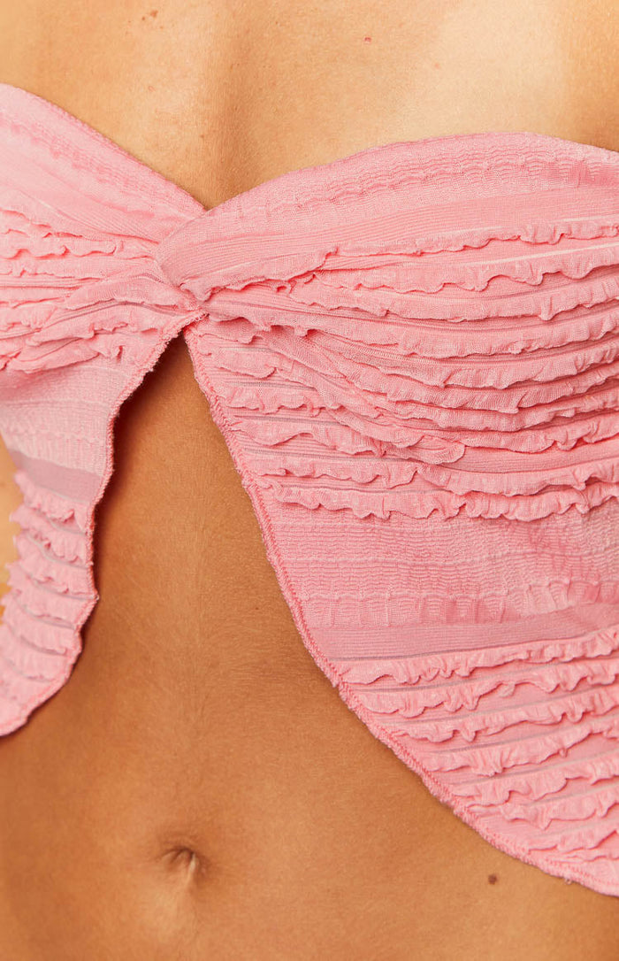 Close-up of the pink strapless top showing the textured, ruffled fabric and twisted front detail