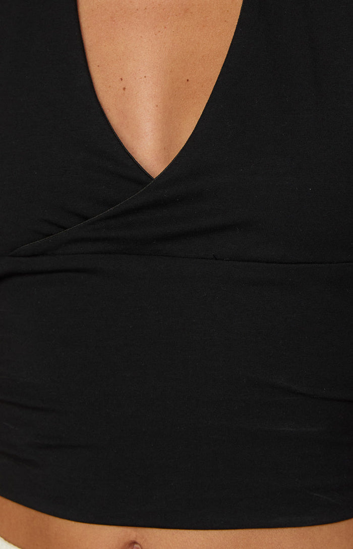 Close-up of the black wrap V-neckline and fitted band with horizontal seam on a crop top