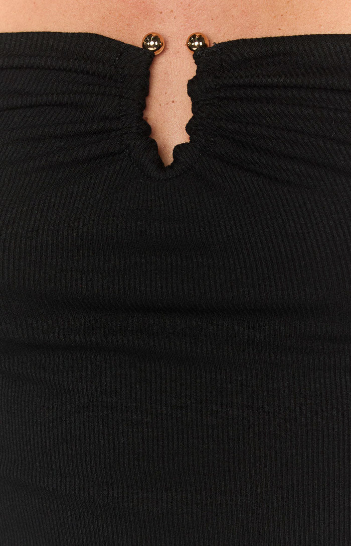 Close-up of the black ribbed knit top's ruched V-neckline with two gold sphere details