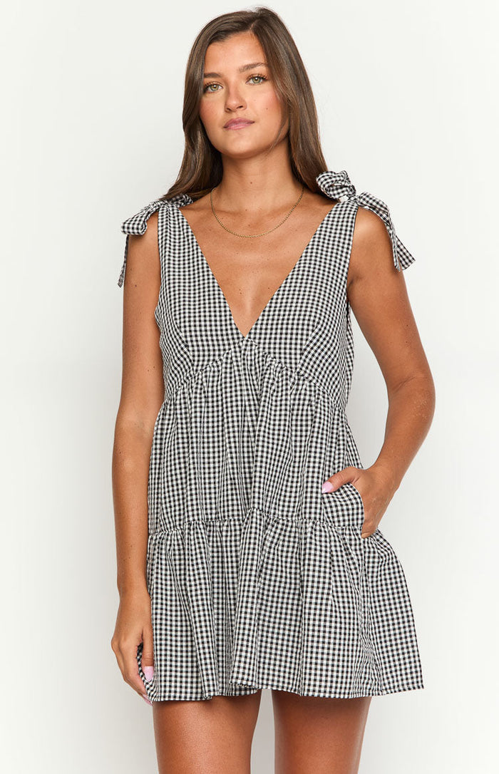 Black gingham mini dress with a deep V-neck, tie shoulders, gathered waist, tiered skirt, and side pockets
