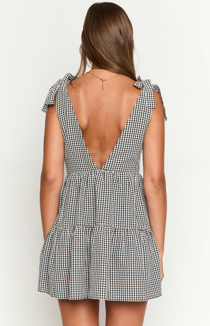 Rear view of a black gingham mini dress showing the deep V-back, tie-shoulder straps, and tiered skirt