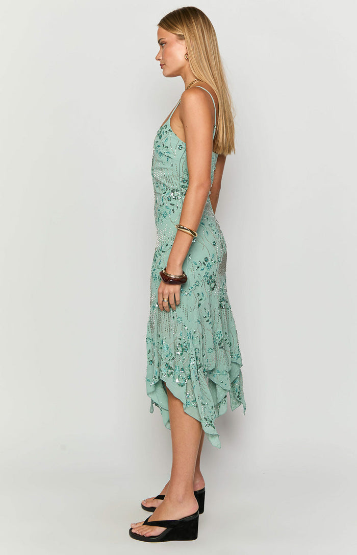 Side view of a teal sequin midi dress with spaghetti straps and a flowy asymmetrical handkerchief hem