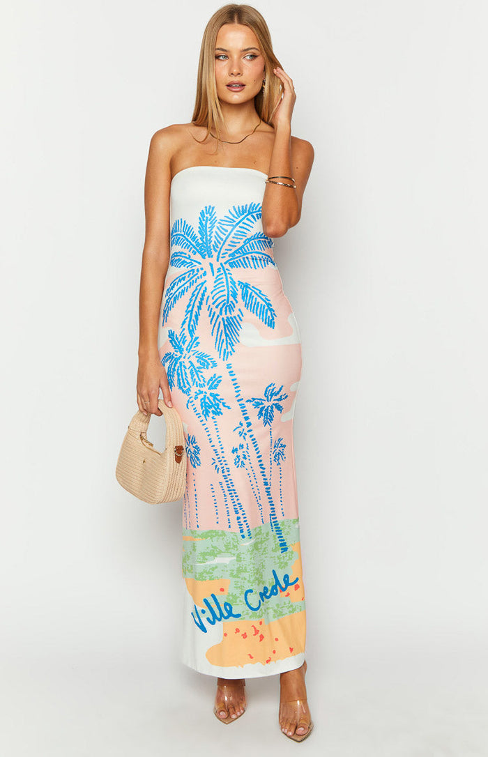 Front view of a strapless bodycon maxi dress with blue palm trees, pink sky, and 'Ville Crede' text