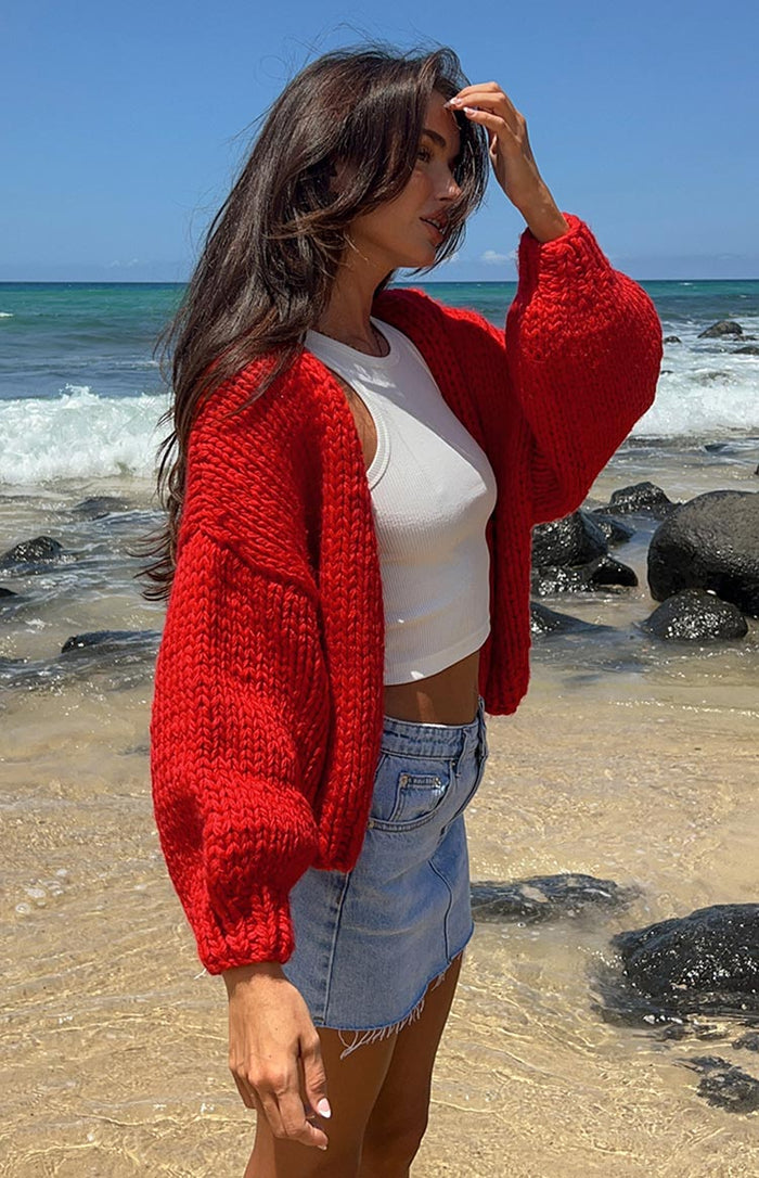 Front view of a relaxed fit red chunky knit cardigan with long sleeves, worn open
