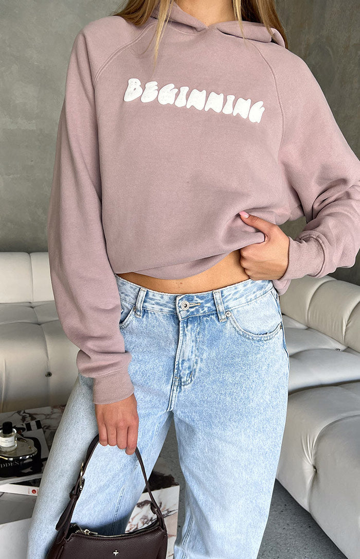 Front view of the cropped beige hoodie with white BEGINNING text, raglan sleeves, and ribbed cuffs