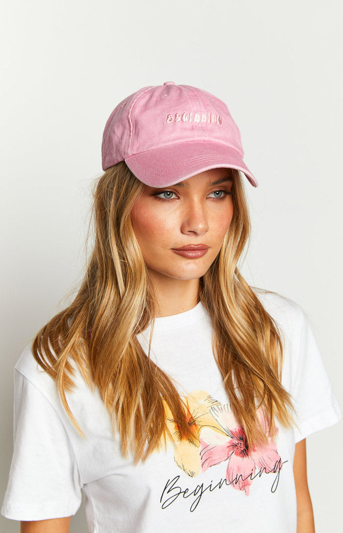 Angled view of the pink washed cap showing the distressed brim and raised embroidered Beginning text