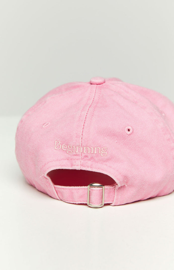 Rear view of a pink washed cap showing the embroidered Beginning text and silver adjustable buckle