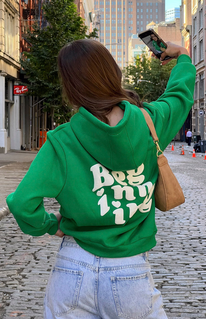 Rear view of a green hoodie with a white 'Beginning' graphic print and heart details on the back