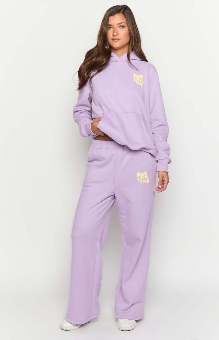 Full length view of a purple oversized hoodie with a relaxed fit, kangaroo pocket, and yellow chest logo