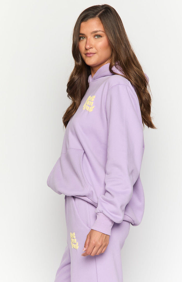 Side view of a purple hoodie with yellow 'Feeling Fine' text on the chest and a kangaroo pocket