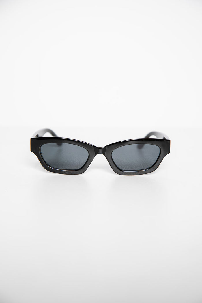 Black slimline sunglasses with dark grey lenses and an angular frame from a slightly elevated perspective