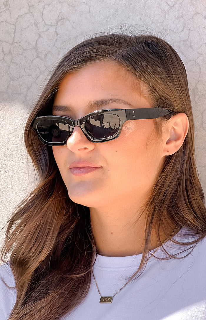Beginning Boutique Black Slimline Sunglasses black slimline sunglasses with a subtle cat-eye shape and dark lenses