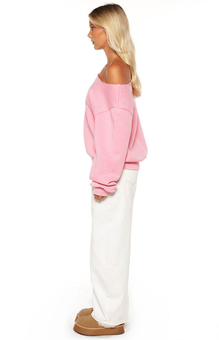 Side view of a pink off-shoulder sweater with an oversized fit, long sleeves, and ribbed cuffs and hem