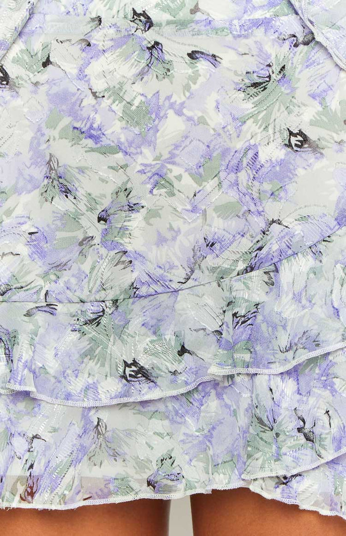 Close-up of the purple and green floral print chiffon fabric with subtle texture and tiered ruffles