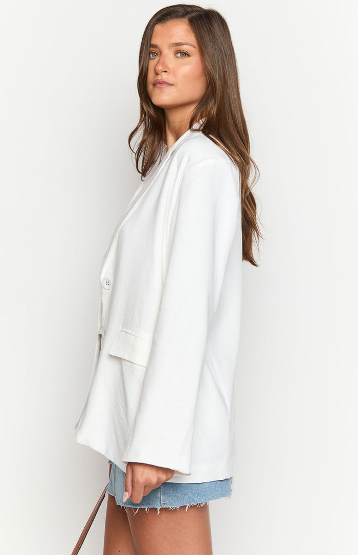 Side view of an oversized white linen blend blazer with a single button closure and flap pocket