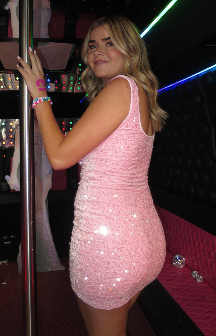 Side view of a pink sequin mini dress with a bodycon fit and ruched detailing on the side and back