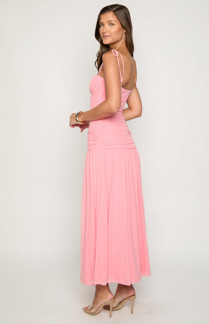 Side view of a pink ruched maxi dress with tie-shoulder straps and a flowy skirt