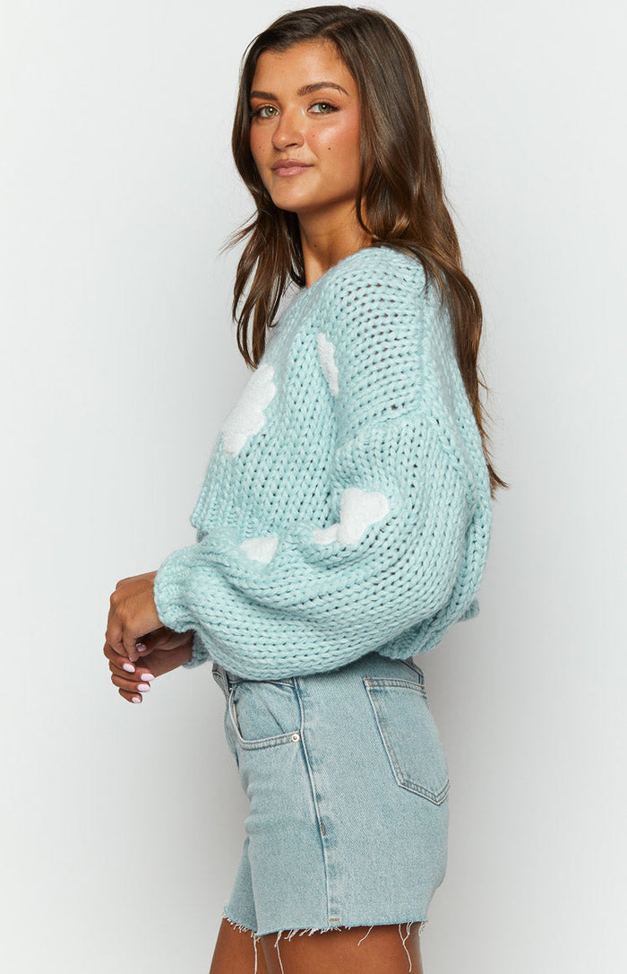 Side view of a light blue chunky knit sweater with white cloud patterns and balloon sleeves