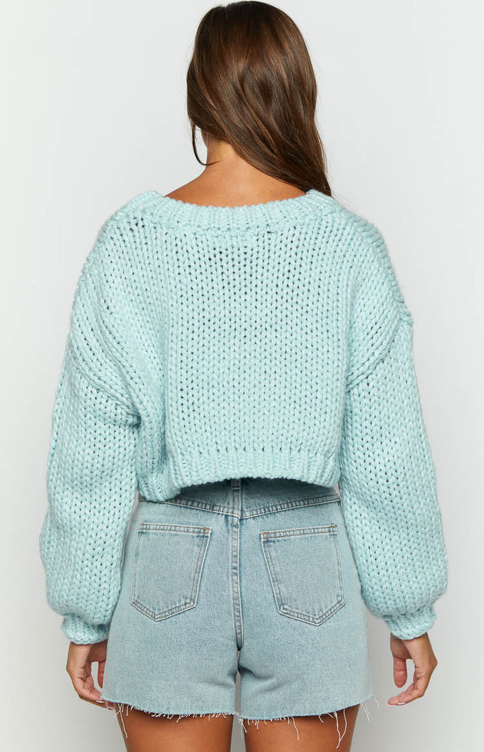 Rear view of a blue chunky knit cropped sweater with wide neckline and voluminous sleeves