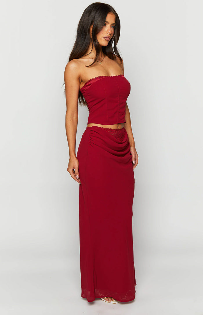 Side-front view of a crimson rose red maxi skirt with a draped front and delicate lace trim at the waist