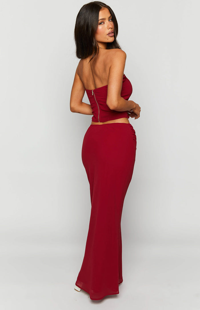 Rear-side view of a crimson red maxi skirt with ruched side detail and a flowy fit
