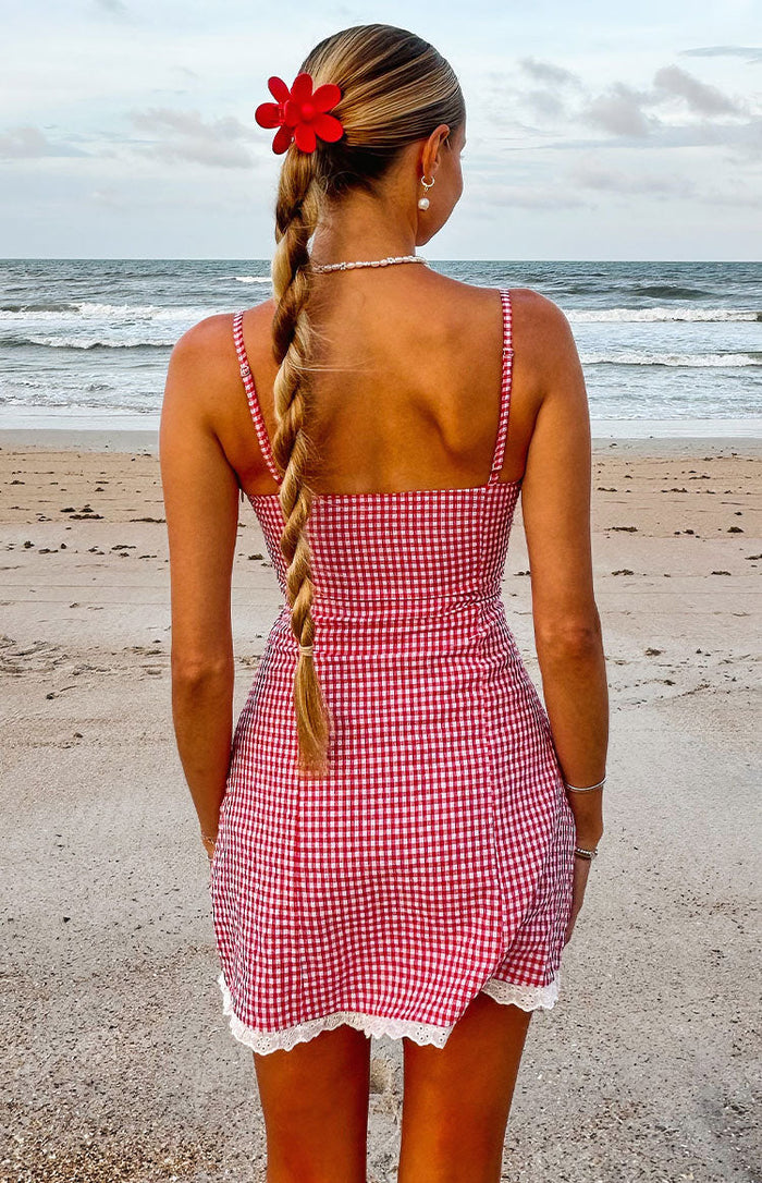 Rear view of a red gingham mini dress with thin spaghetti straps and white lace trim hem
