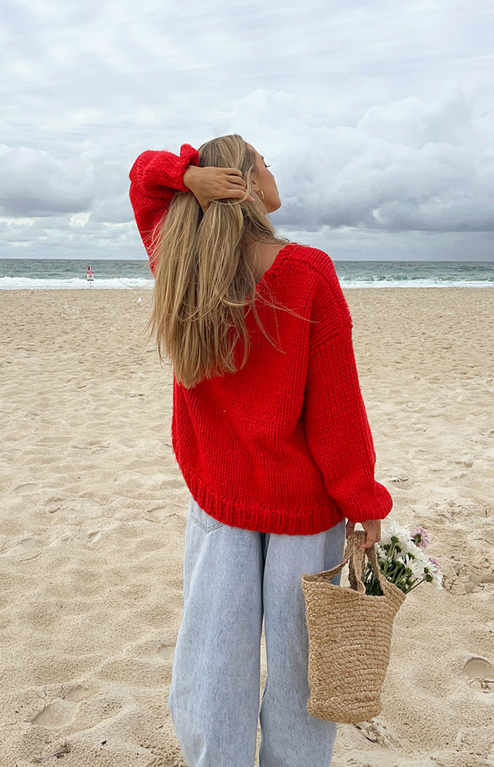 Rear view of a red chunky knit sweater with a V-neckline and ribbed hem