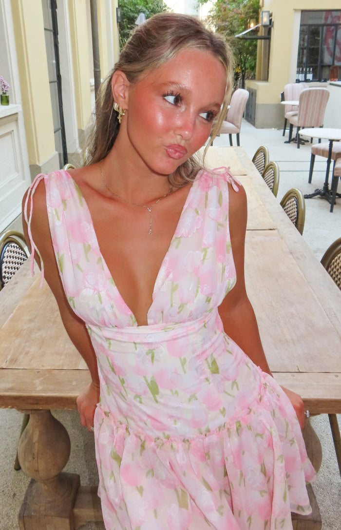 Close-up of the pink floral mini dress with a deep V-neckline, tie-shoulder straps, fitted waist, and ruffled skirt