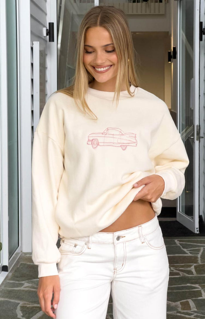 Close-up of the cream crew neck sweater showing the red outline vintage car graphic on the front