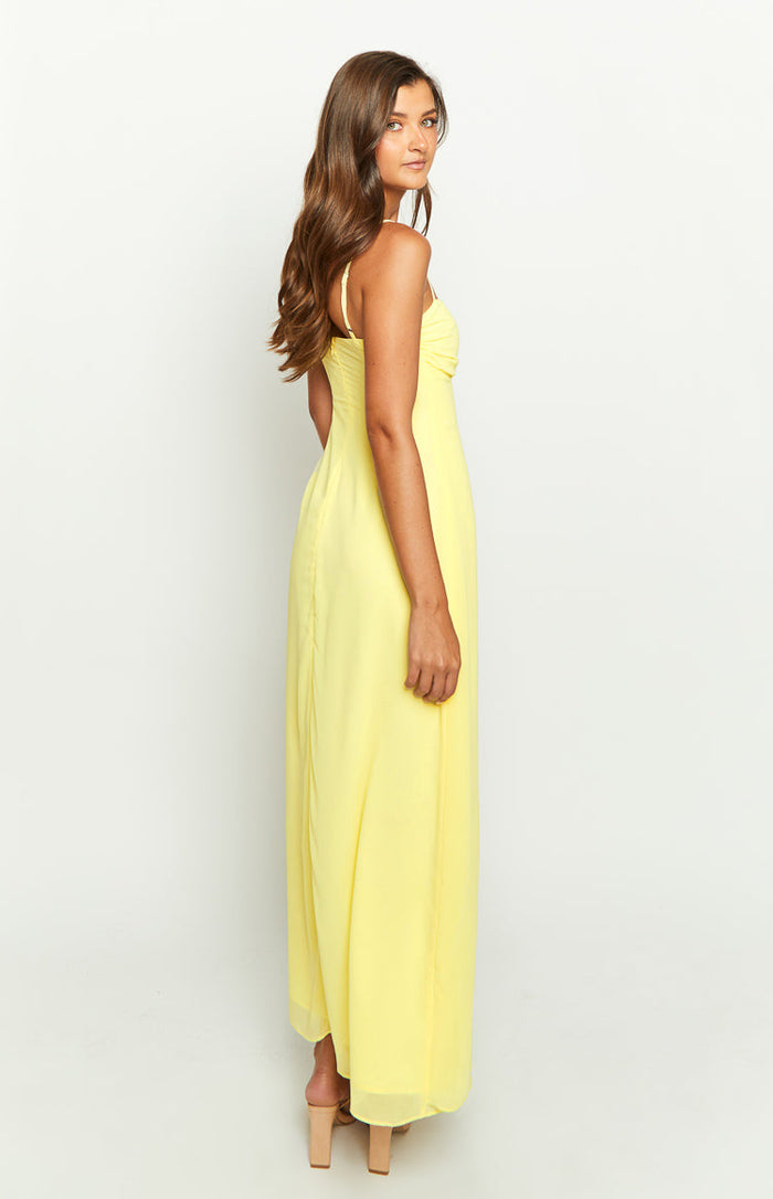 Side view of a light yellow sleeveless maxi dress with spaghetti straps and a flowy skirt
