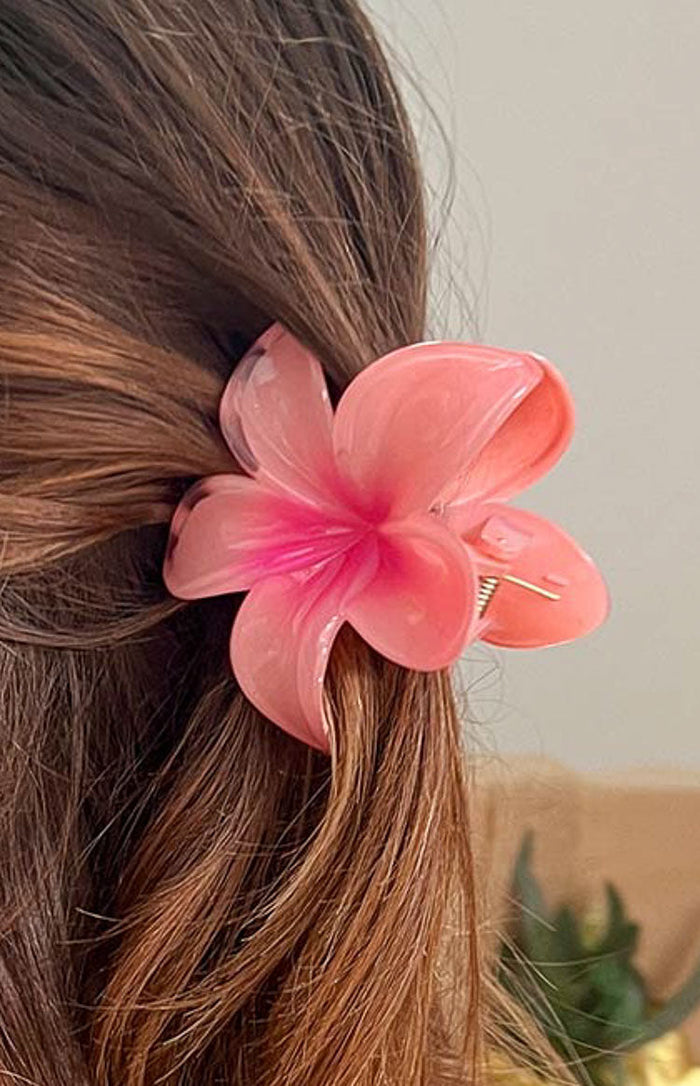 Side view of a glossy pink frangipani flower claw clip with a darker pink center