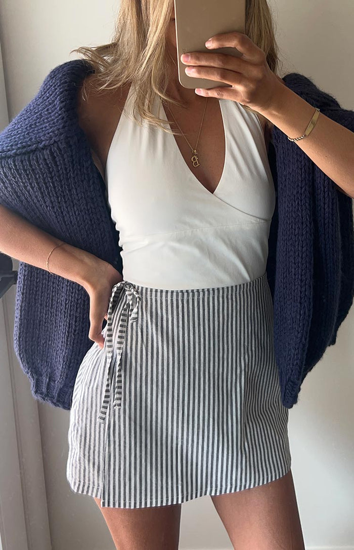 Close-up of the tie-side detail on a blue narrow vertical stripe linen-look mini skirt