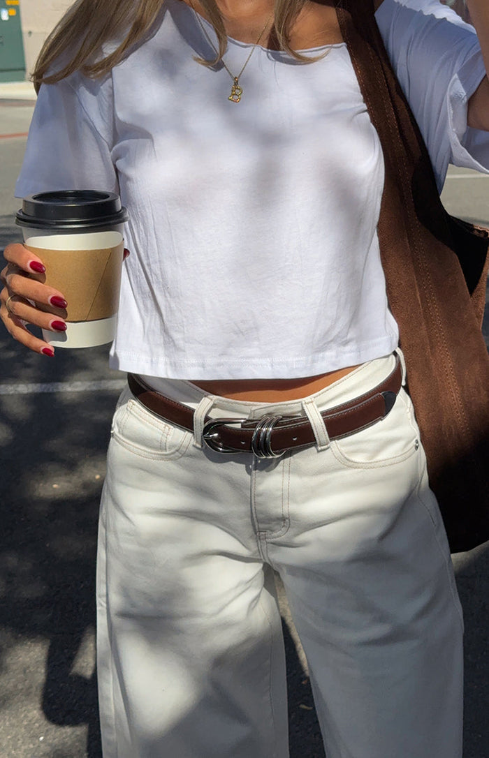 Close-up of the white denim barrel leg jeans waistband with belt loops and visible light contrast stitching