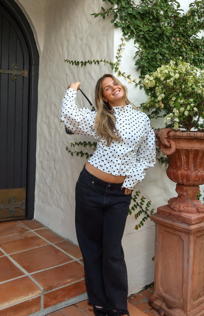 Front view of a white polka dot jacket with a high neck, voluminous puff sleeves, and a cropped hem