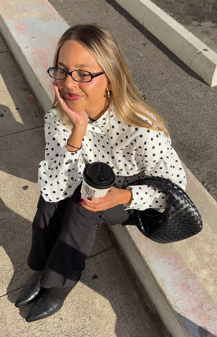 White polka dot jacket featuring a high neck bow, gathered shoulders, and voluminous buttoned cuffs