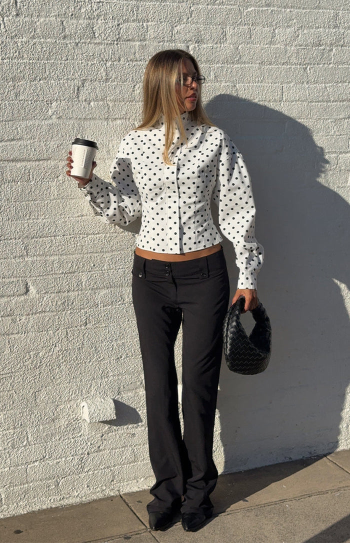 Front view of a white polka dot jacket with a high neck, fitted bodice, and puff long sleeves
