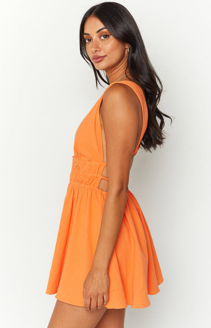 Side view of an orange crinkle mini dress with deep V-neck, sleeveless design, side cutouts, and a ruched elastic waist