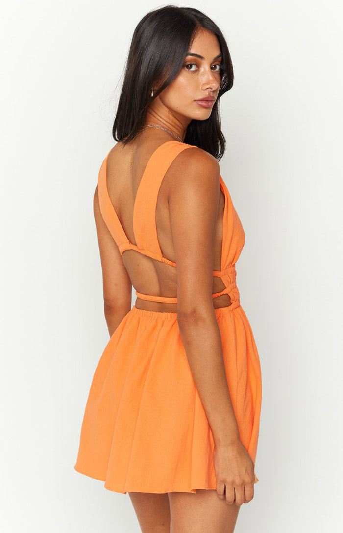 Rear view of an orange crinkle mini dress featuring wide shoulder straps, a low back, and elasticated waist cutouts